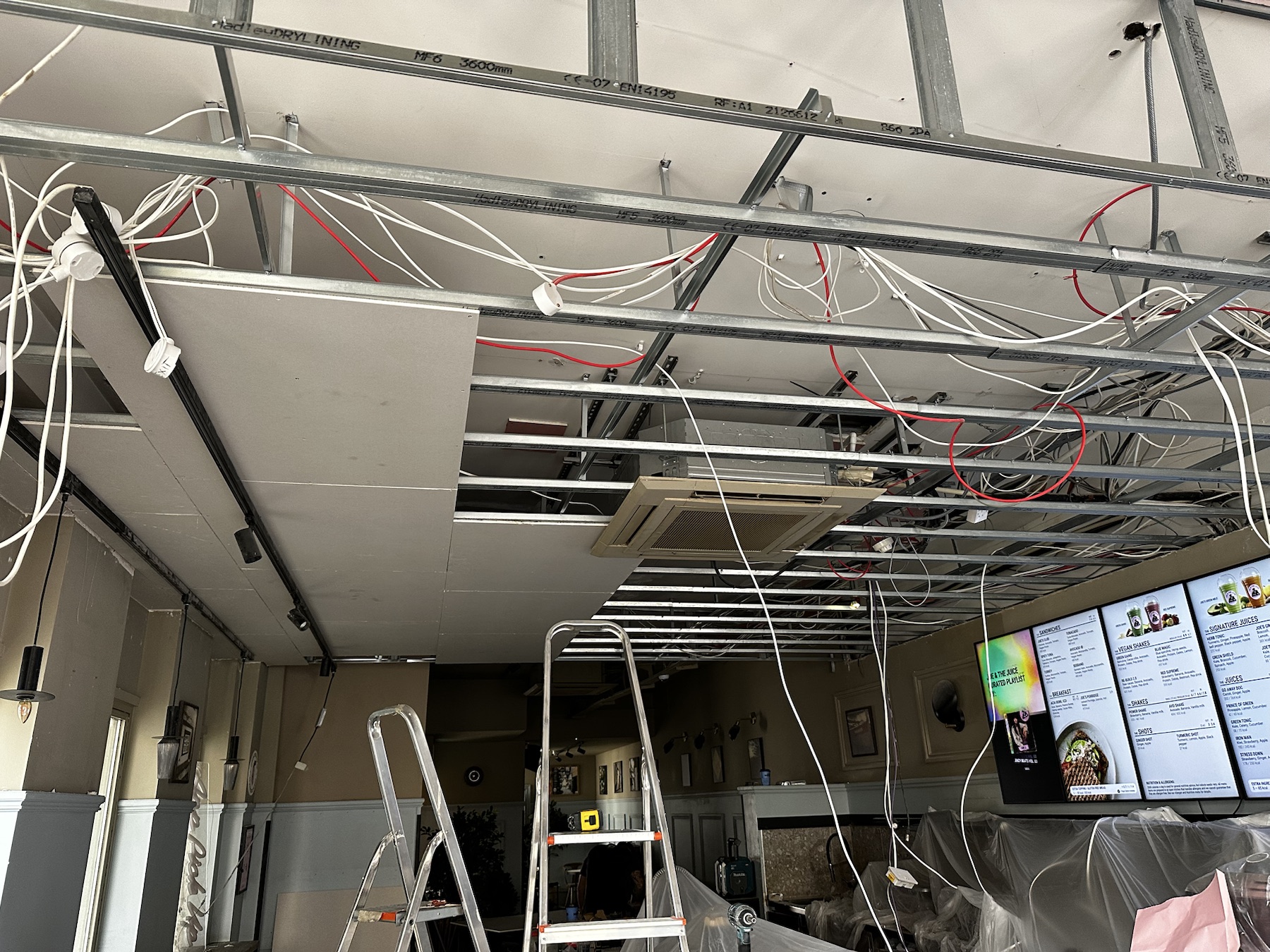 Plasterboard being installed to the new metal ceiling framework