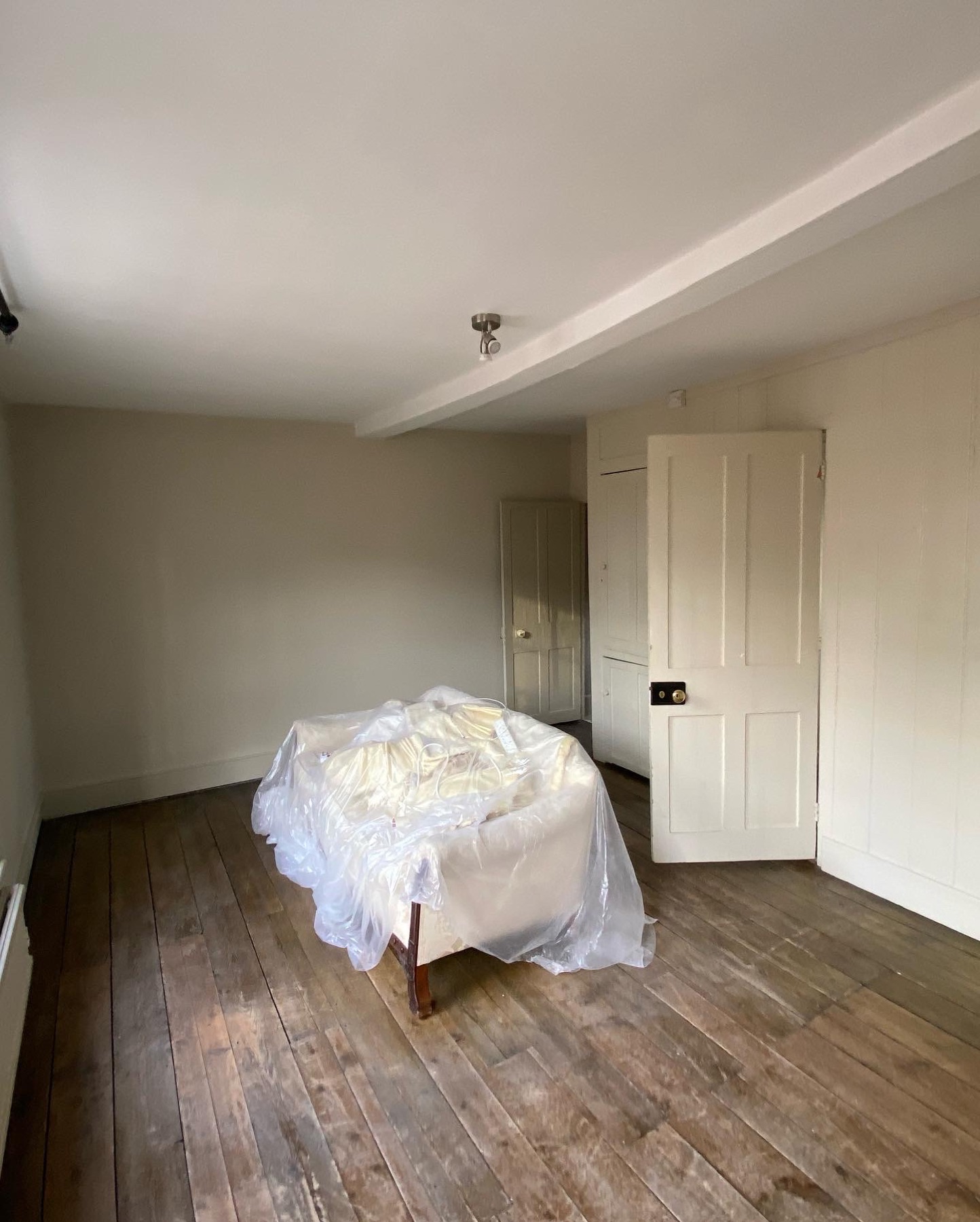 Neutral painted bedroom with timber floor and panelled cupboards